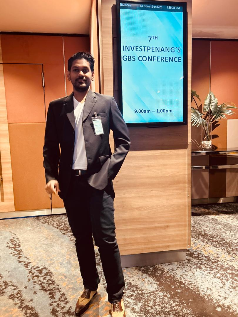 Photograph beside the board for the 7th InvestPenang’s GBS Conference, displaying 13 November 2025